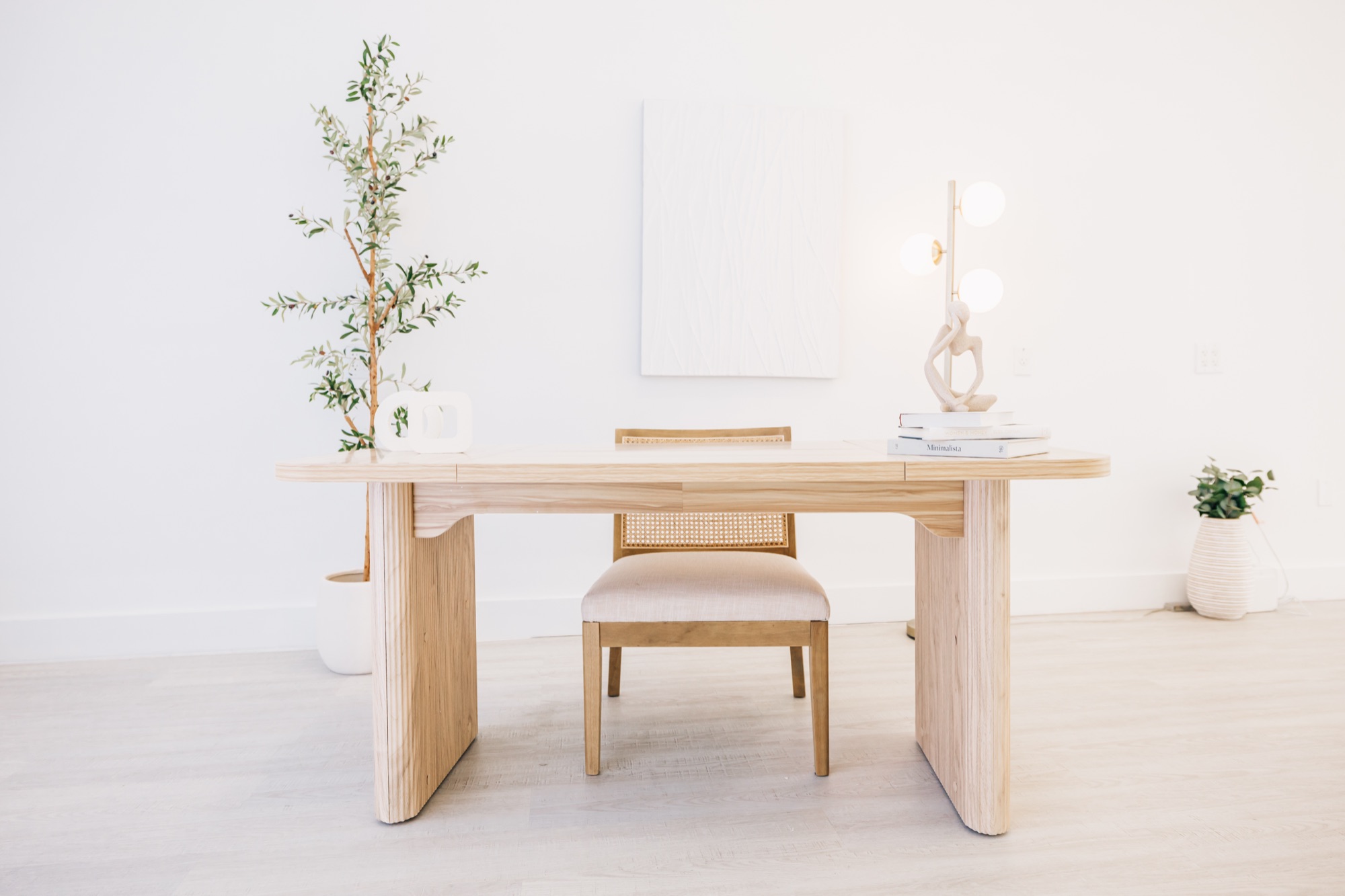 Branding desk corner with a wooden table, chair, olive plant, and table lamp