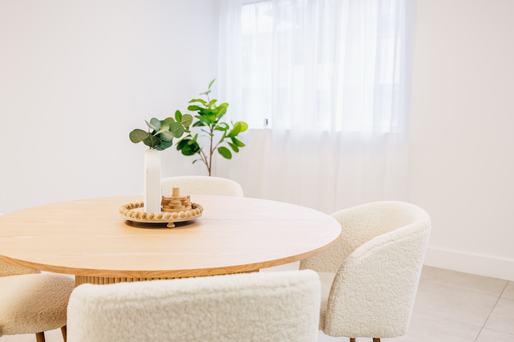 Round wooden table with two bouclé chairs beside the kitchenette