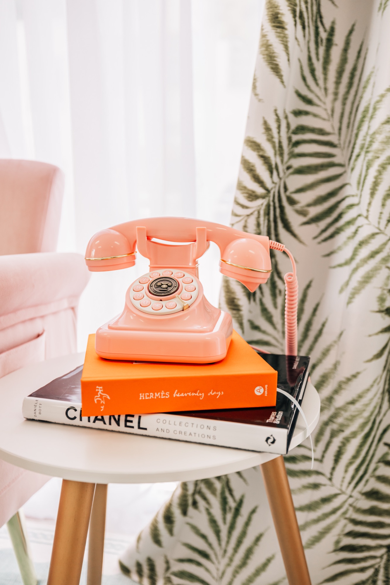 Styling detail on the pink set — a vintage pink telephone and fashion book on a side table